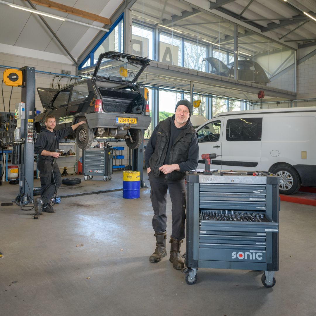Werkcentrum functionele fotografie twee medewerkers in garage met gereedschapskist op wieltjes